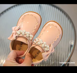 Close-up of pink patent leather Mary Jane shoe with bow, pearl and rhinestone details