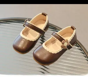Detail of brown Mary Jane shoes for girls featuring a 3D floral accent and soft rubber sole