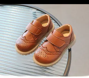 Detailed side view of brown velcro leather shoes for kids with brogue carving details