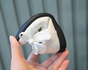 Detail showing the ultra-flexible black soft sole of a white bow princess shoe