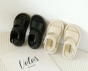 Détail de sandales minimalistes pour enfants en noir et beige sur tissu gaufré blanc