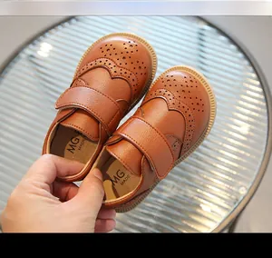 Detailed macro view of soft brown leather kids' brogue shoes with velcro strap closure