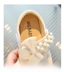 Detail of white Mary Jane shoes for girls featuring pearl bow and velcro strap design