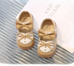 Détail de chaussures de princesse kaki avec nœud et dentelle en cœur sur semelle souple