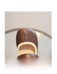 Detailed close-up of brown Mary Jane shoes featuring scalloped trim and a round toe design