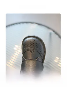 Detail of children's matte leather shoes with classic Brogue perforation on round toe