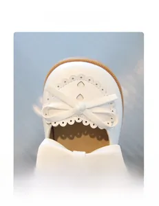 Détail de chaussure blanche pour fille avec cœur découpé et nœud délicat sur l'avant