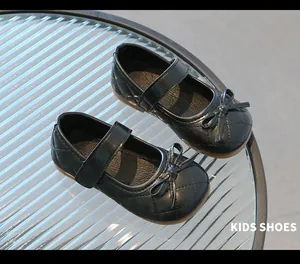 Détail de ballerines noires pour filles avec motif matelassé et nœud sur table