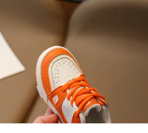 Gros plan détaillé de baskets en cuir orange et blanc pour filles avec motif latéral L