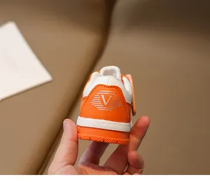 Détail de baskets enfants orange et blanc avec logo en V et renfort de talon surpiqué