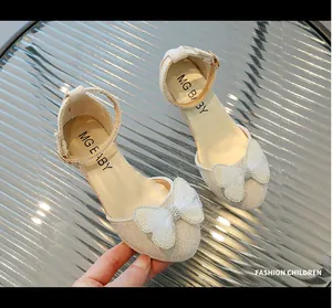 Dettaglio delle scarpe bambina in mesh beige con grande fiocco di strass e perle