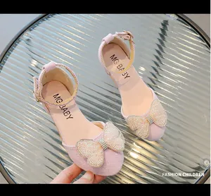Dettaglio scarpa rosa da bambina con decorazione a fiocco in perle e strass scintillanti