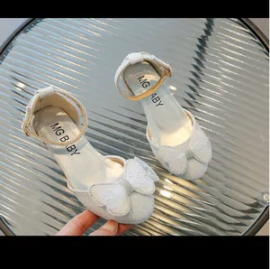 Dettaglio di scarpe da principessa per bambine in paillettes argento con fiocco in rete
