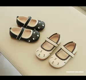 Top view of girls' black and beige Mary Jane shoes with floral embroidery and wavy edges