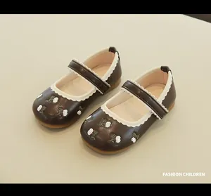 Macro detail of dark brown Mary Jane shoes with floral embroidery and scalloped trim