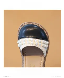 Dettaglio scarpe bimba con decorazioni di perle e punta rotonda nera anti-collisione