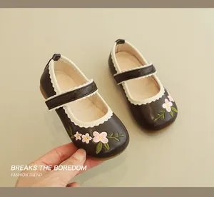 Detail of girls brown Mary Jane shoes with floral embroidery and wavy ruffle trim
