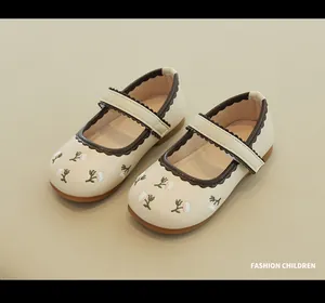 Detail of girls' Mary Jane shoes featuring floral embroidery and wavy scalloped trim