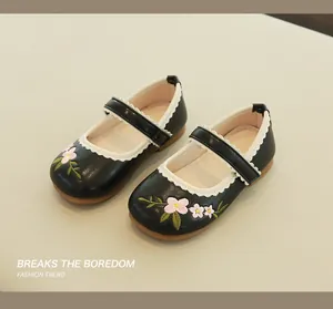 Detail of girls' black Mary Janes featuring pink flower embroidery and wavy white stitching