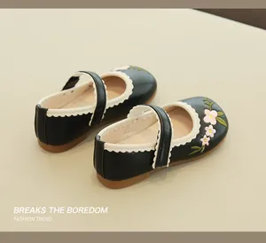 Detail of girls' black Mary Janes featuring pink floral embroidery and scalloped edges