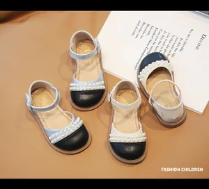 Dettaglio di scarpe Mary Jane da bambina con cinturini di perle e design bicolore
