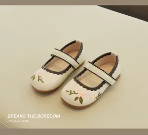 Detail of embroidered floral patterns and velcro strap on girl's Mary Jane leather shoes