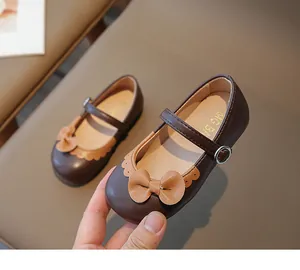 Nahaufnahme der braunen Mary Jane Lederschuhe mit Lederschleife und Metallschnallenriemen