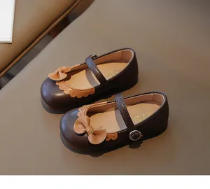 Detail von Mädchen Mary Jane Schuhen mit Schleife und Wellenrand auf braunem PU-Leder