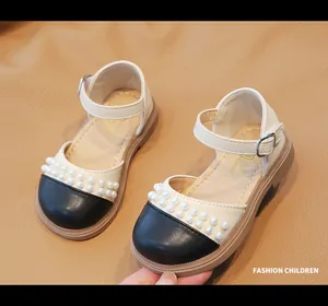 Dettaglio di scarpe Mary Jane per bambine con cinturini di perle e punta rotonda nera