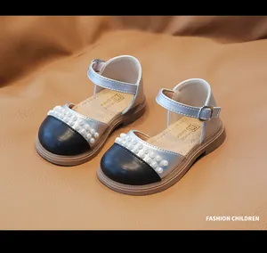 Dettaglio scarpe Mary Jane da bambina con perle e finitura argento su pelle marrone