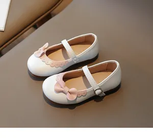 Detail von weißen Mädchen-Mary-Janes mit rosa Schleife und gewelltem Rand-Finish
