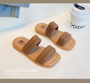 Detail of brown puffy double-strap girls' summer sandals on denim background