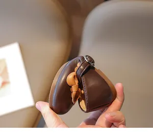 Nahaufnahme flexibler brauner Mädchen-Flachschuh, gebogen zur Demonstration der weichen Sohle