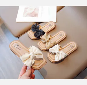 Close-up of girls' open-toe slippers with bow decoration in black, khaki, and beige colors