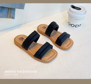 Detail view of girls black padded soft strap summer sandals on a textured summer background