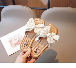 Close-up of kids bow-knot slide sandals with cream PU upper and square toe design