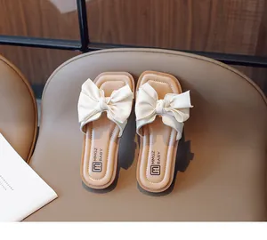 Close-up of a stylish cream open-toe kid's sandal featuring a large decorative bow detail
