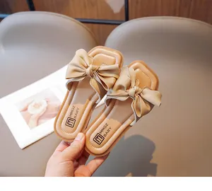 Detail shot of girls' beige open-toe sandals with a large silk bow and square toe design