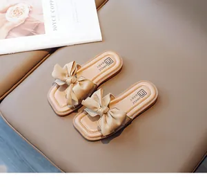 Detailed top view of soft beige girls' open-toe slippers with a large decorative bow detail