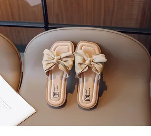 Close-up of beige girl sandals featuring a large bow and a soft open-toe square sole