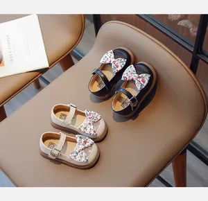 Flache Ansicht von Mary Jane Schuhen mit Blumen-Schleifen in Schwarz und Beige auf Leder