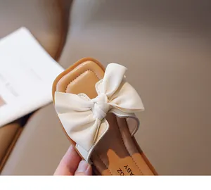 Detail of children's square toe sandals with a large cream bow and soft stitched soles