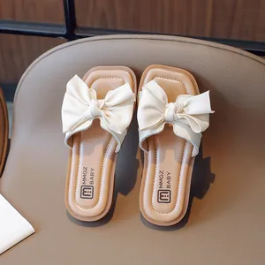 Chic girls' open-toe sandals in cream white with a large bow on brown leather seat