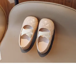 Dettaglio di ballerine trapuntate beige per bambini con cinturini elastici incrociati