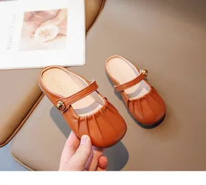 Detail of girls tan Mary Jane mules featuring ruffled toe and vintage gold buckle
