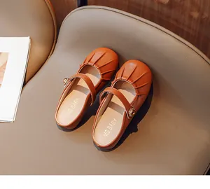 Close-up of orange-brown Mary Jane slippers with pleated texture and gold buckle