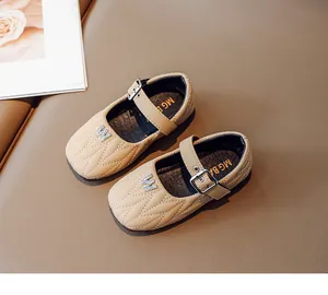 Close-up of girls' quilted beige Mary Jane shoes with rhinestone letter and metal buckle