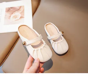 Macro shot of girls cream Mary Jane slippers with pleated toe and golden buckle