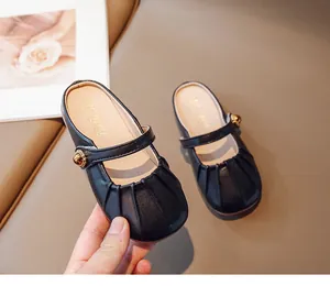 Detail of girls' black Mary Jane mule shoes with pleated toe and gold ornament