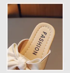 Dettaglio delle pantofole da bambina con suola morbida, fiocco in pelle crema e cuciture